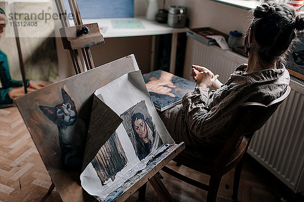 Künstlerin sitzt mit Gemälden in ihrem Atelier