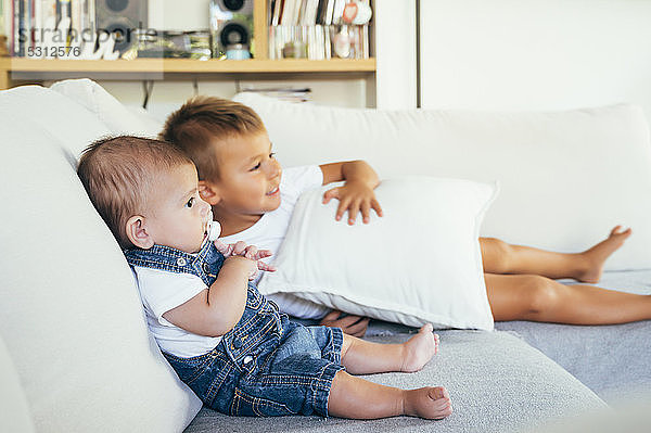 Zwei Jungen sitzen auf dem Sofa und schauen zu Hause fern