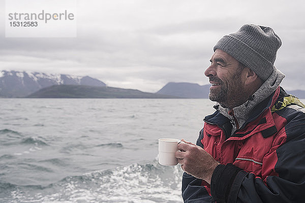 Erwachsener Mann schaut aufs Meer  Bootfahren auf dem Eyjafjordur Fjord  Island