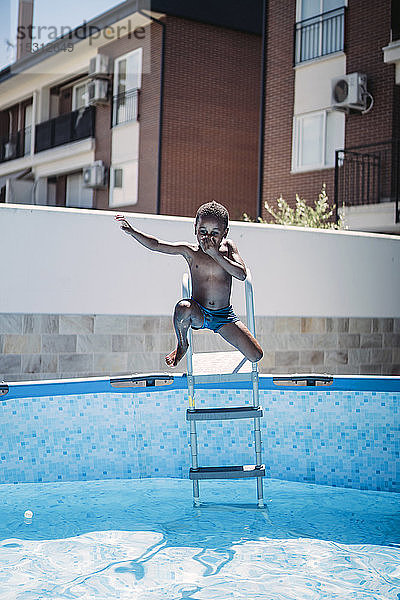 Glücklicher kleiner Junge auf einer Leiter des Schwimmbads