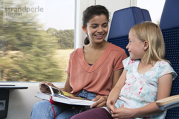 Zwei Schwestern sitzen in einem Zug und lesen ein Buch