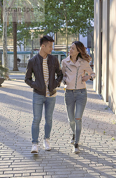 Ehepaar in Jeans und Lederjacken geht abends auf der Straße