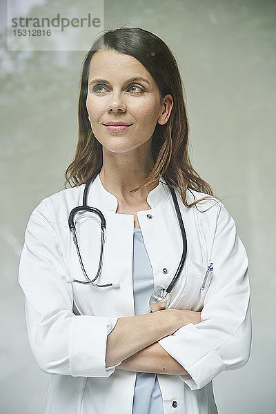 Porträt einer selbstbewussten Ärztin hinter einer Fensterscheibe