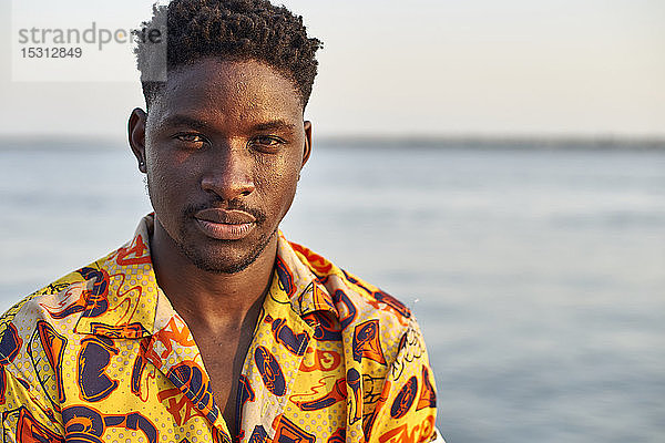 Am Meer stehender junger Mann  Porträt