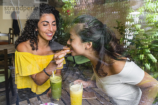 Lächelnde junge Frau in einem Café  die mit ihrem Freund einen Keks teilt