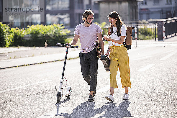 Junges Paar mit Elektroroller und Smartphone auf der Straße