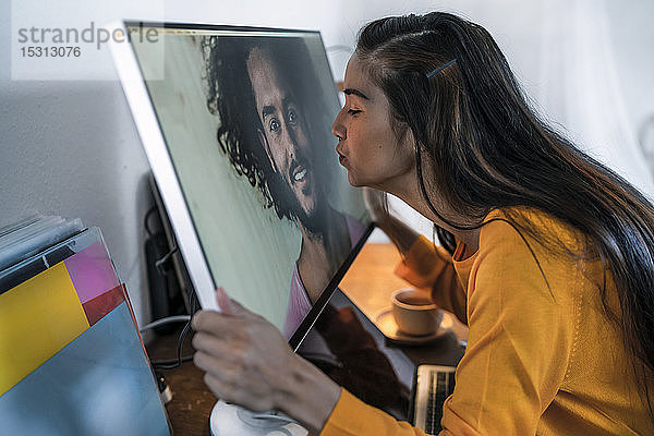Junge Frau küsst Mann auf Computerbildschirm
