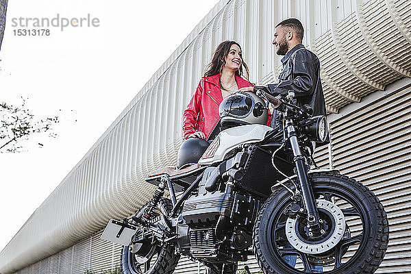 Paar mit Motorradhelmen neben dem Motorrad stehend