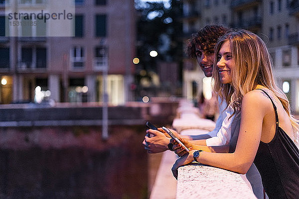 Glückliches junges Paar lehnt nachts am Brückengeländer  Verona  Italien