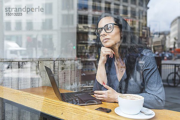 Geschäftsfrau  die in einem Café eine Pause macht und mit einem Laptop arbeitet