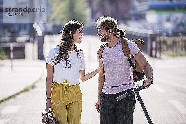 Junges Paar mit Elektroroller im Gespräch auf der Straße