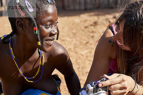 Weiße Frau  die einer Frau vom Mudimba-Stamm ein Bild mit ihrer Kamera zeigt  Canhimei  Angola