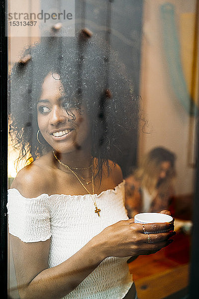Frau mit einer Tasse Kaffee  die aus dem Fenster schaut  in einem Cafe