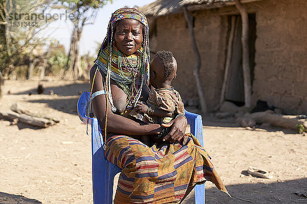 Muhila traditionelle Frau  die auf einem blauen Stuhl sitzt  mit Baby auf dem Schoß  Congolo  Angola.