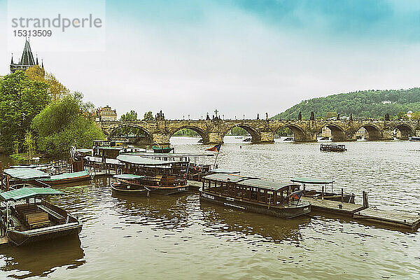 Blick auf die Karlsbrücke mit vertäuten Ausflugsbooten im Vordergrund  Prag  Tschechische Republik