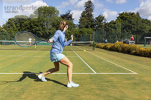 Reife Frau während eines Tennisspiels auf Rasen