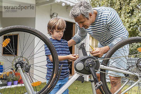 Vater und Sohn reparieren ein Fahrrad im Garten