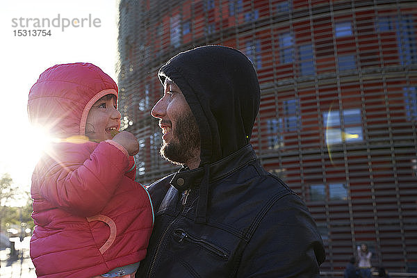 Glücklicher Vater hält seine Tochter bei Sonnenuntergang im Winter in der Stadt  Barcelona  Spanien