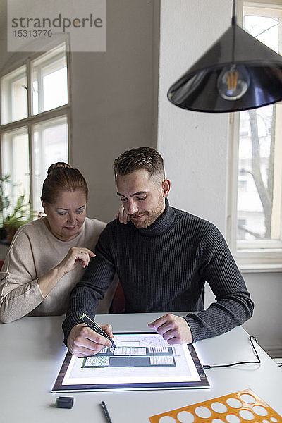 Ältere Frau beobachtet Mann mit Tablett mit Architekturplan