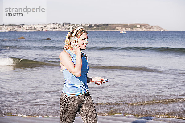 Joggerin am Strand  mit Smartphone und Kopfhörern