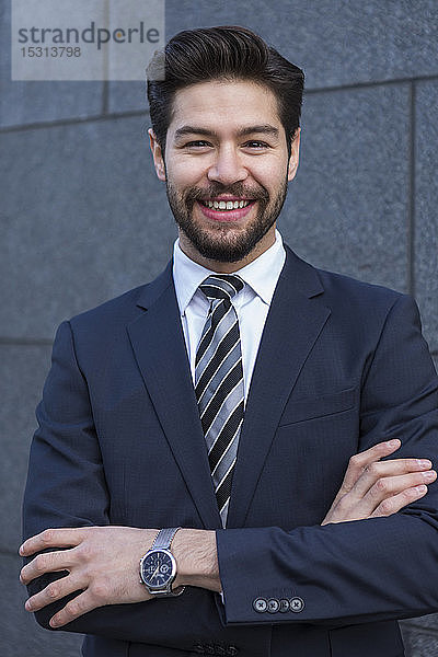 Porträt eines bärtigen jungen Geschäftsmannes in blauem Anzug  Jackett  Krawatte und Armbanduhr