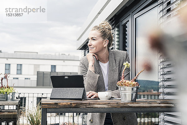 Geschäftsfrau mit Tablette auf der Dachterrasse bei einer Pause