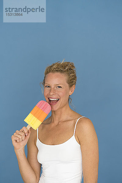 Bildnis einer blonden Frau mit großem Eis am Stiel  blauer Hintergrund