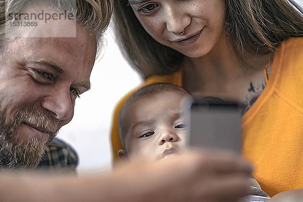 Familie mit Baby benutzt Mobiltelefon