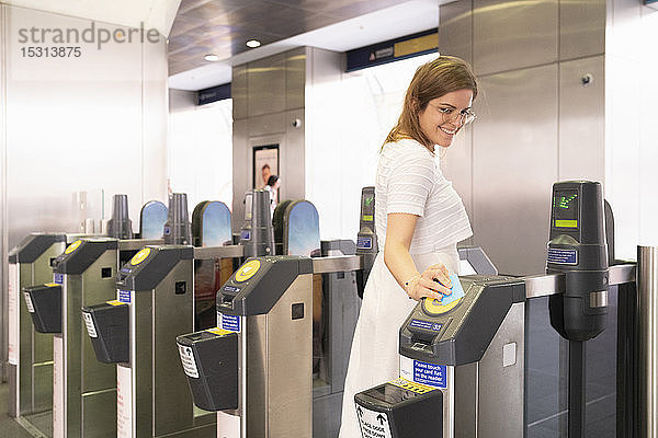 Lächelnde Frau passiert U-Bahn-Gate mit elektronischem Ticket