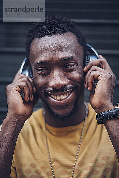 Porträt eines glücklichen Mannes  der mit Kopfhörern Musik hört