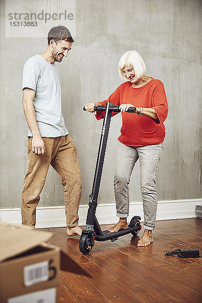 Ältere Frau probiert ihren neuen E-Scooter aus  Garndson assistiert