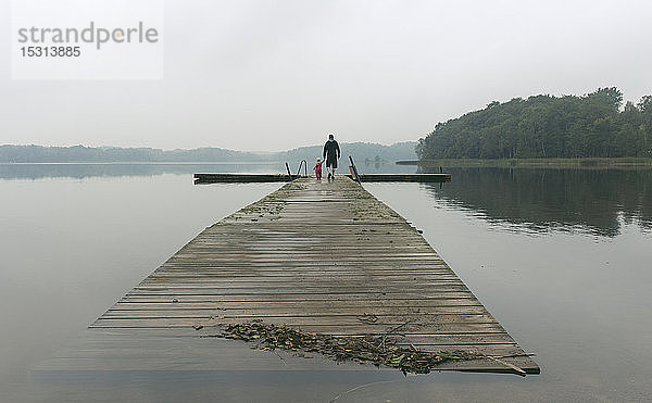 Vater und eine Kleinkind-Tochter spazieren an der Uferpromenade eines Sees  Bezirk Skane  Schweden