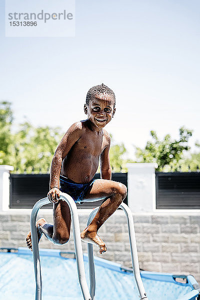 Glücklicher kleiner Junge auf einer Leiter des Schwimmbads