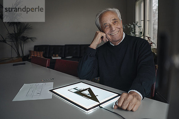 Lächelnder älterer Mann benutzt Tablett mit Architekturplan