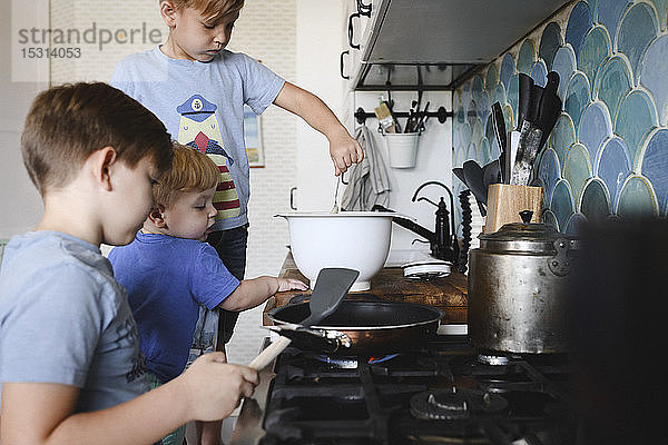Drei Brüder kochen Pfannkuchen in der Küche