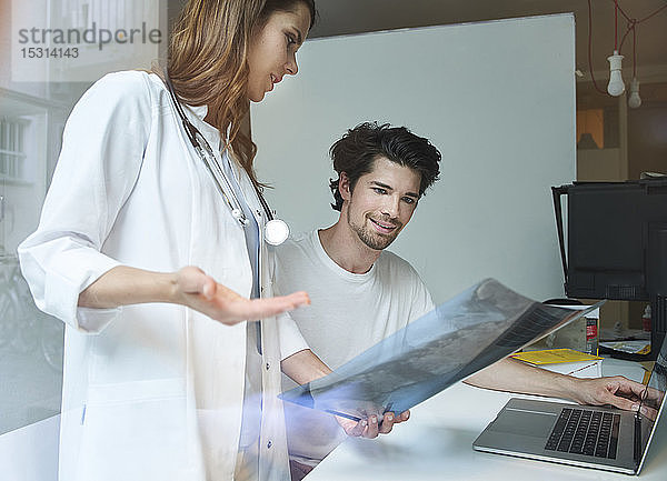 Zwei Ärzte besprechen Röntgenbild am Schreibtisch