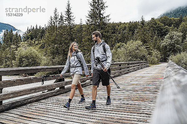 Junges Paar auf einer Wanderung zu Fuß auf einer Holzbrücke  Vorderriss  Bayern  Deutschland
