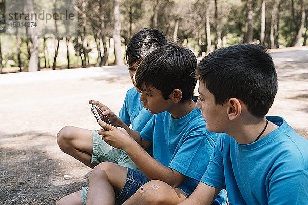 Drei Jungen in blauen T-Shirts mit Smartphone