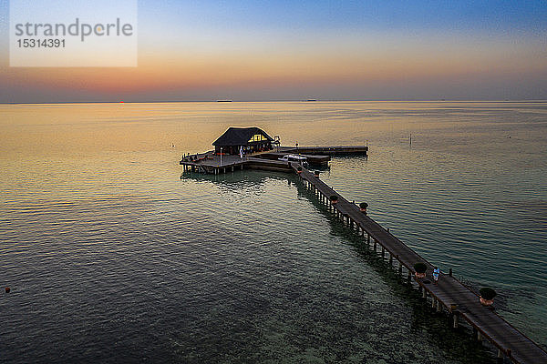 Malediven  Insel Olhuveli  Pier und Gebäude auf der Lagune des Süd Male Atolls bei Sonnenuntergang