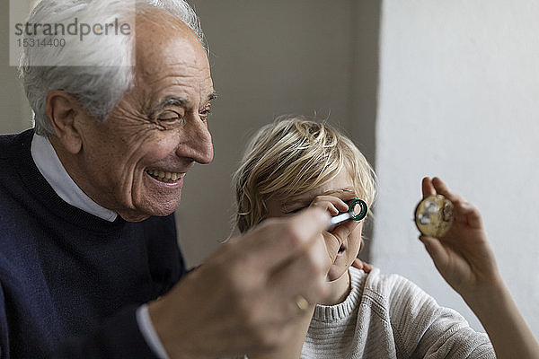 Uhrmacher und sein Enkel beim Blick durchs Okular