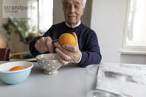 Älterer Mann schält zu Hause Orangen