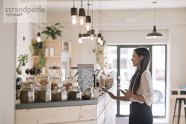 Junge Frau steht am Tresen in einem Café