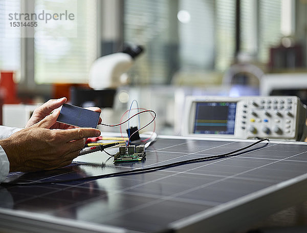 Techniker hält Silizium-Solarzelle auf Solarpanel