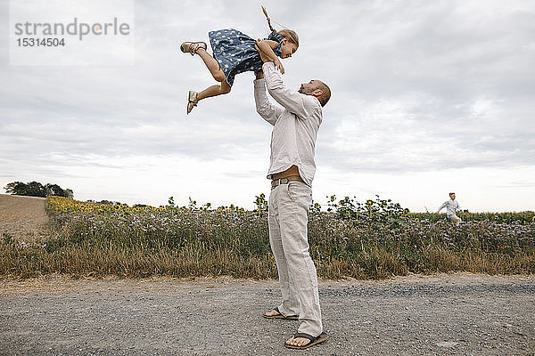 Vater spielt mit seiner Tochter  hält sie in die Höhe