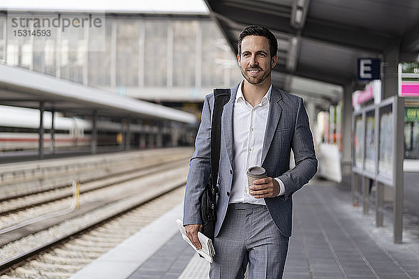 Geschäftsmann mit Kaffee zum Mitnehmen auf dem Bahnsteig