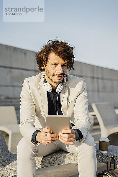 Porträt eines Geschäftsmannes mit Kopfhörer und digitalem Tablet im Freien
