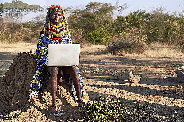 Traditionelle Muhila-Frau  trägt Turnschuhe  arbeitet mit Neakers an ihrem Laptop  Kehamba  Chibia  Angola