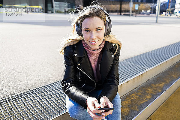 Porträt einer jungen Frau  die mit Smartphone und Kopfhörern Musik hört  Barcelona  Spanien