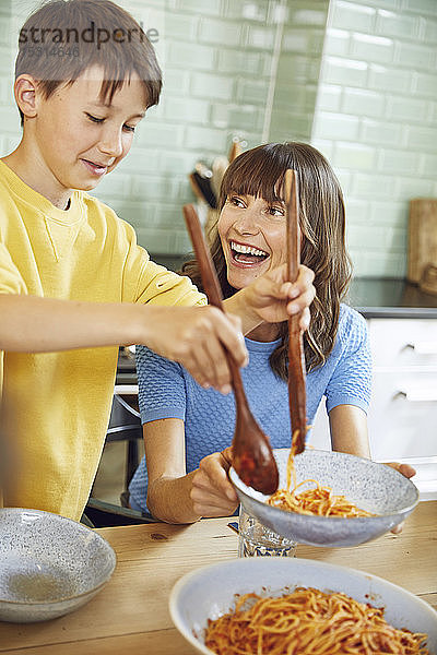Mutter isst Spaghetti mit ihrem Sohn in der Küche
