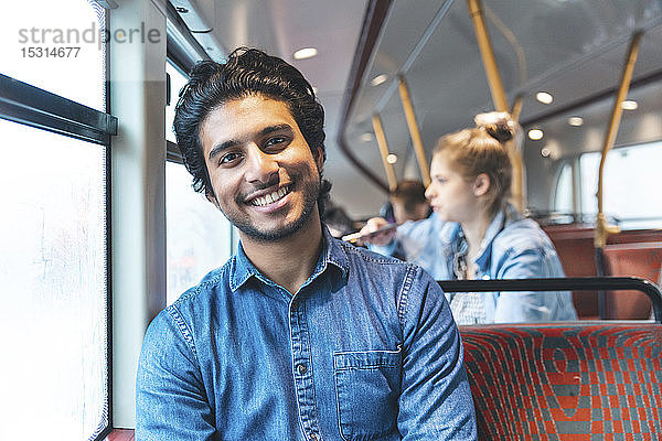 Porträt eines glücklichen jungen Mannes  der mit dem Bus reist  London  UK